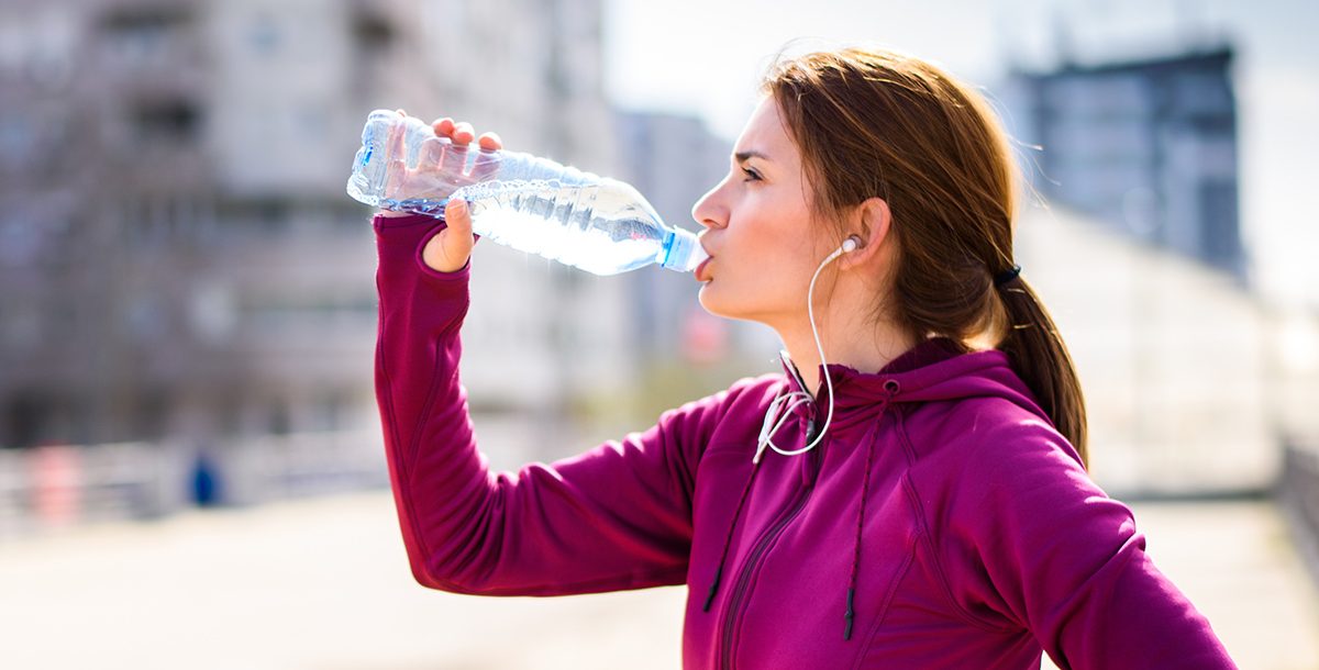 A woman drinking water before a run.