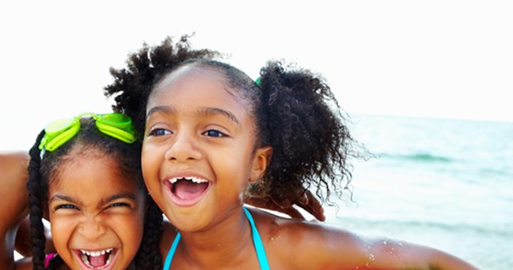 three children playing in the ocean - preventing skin cancer