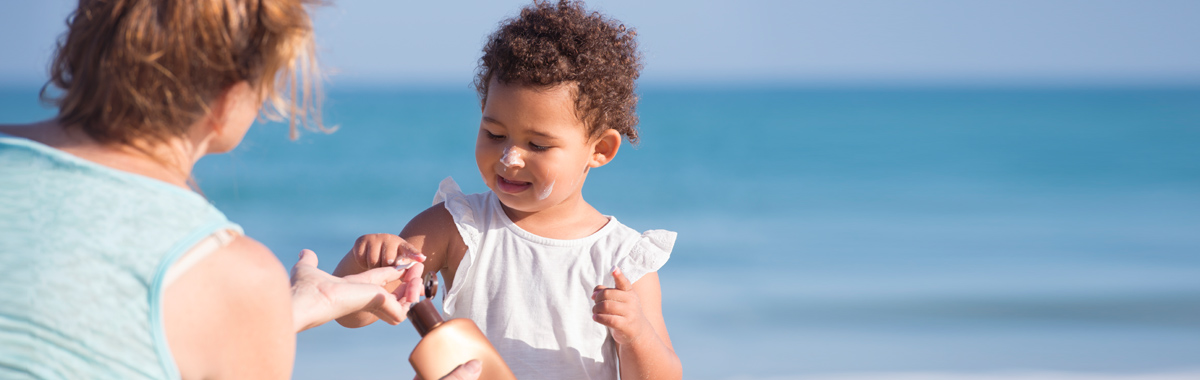 mother helps daughter apply sunscreen_ sun safety tips