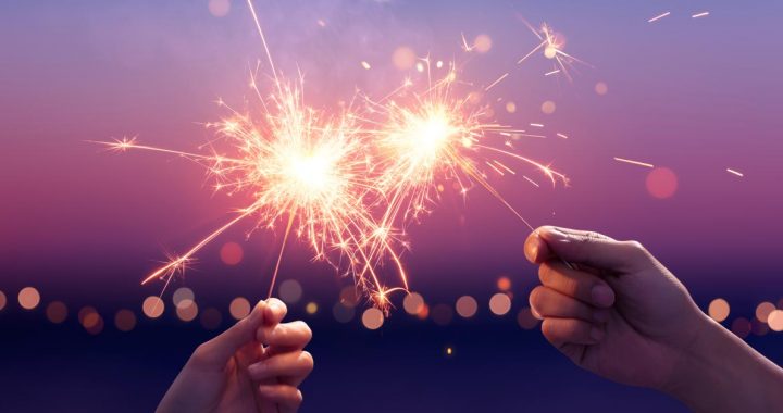 Two people holding sparkler fireworks.