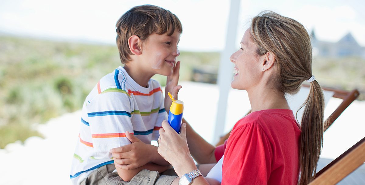 A mother putting sunscreen on her son