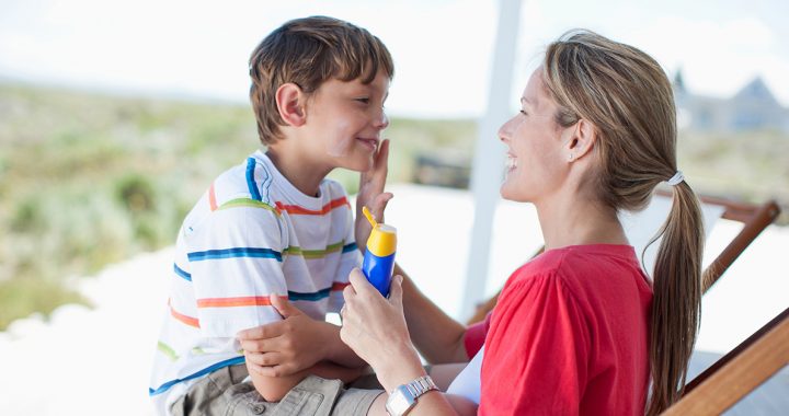 A mother putting sunscreen on her son