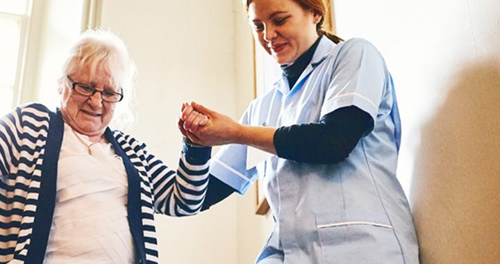 female health care worker helping female patient down stairs after joint replacement