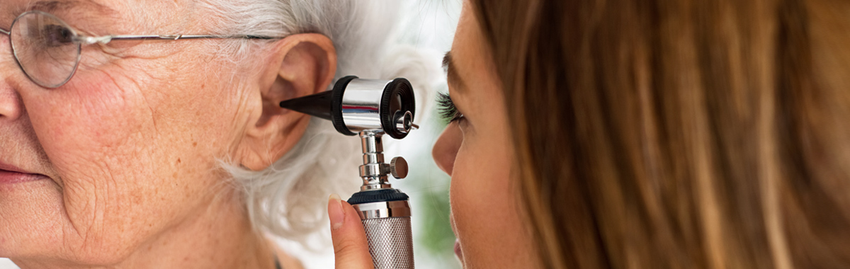 Female ENT provider examining an older female patient's ear