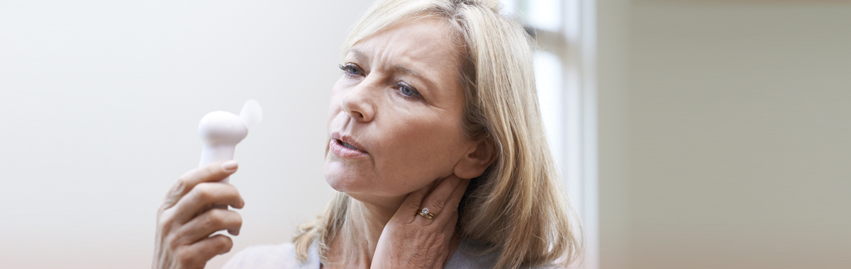 Woman going through menopause holds handheld fan in front of face