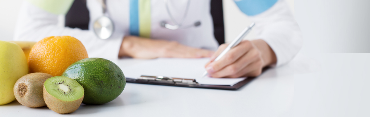 Provider sitting with paper and pen at table with fruits planning a diet for after surgical weight loss