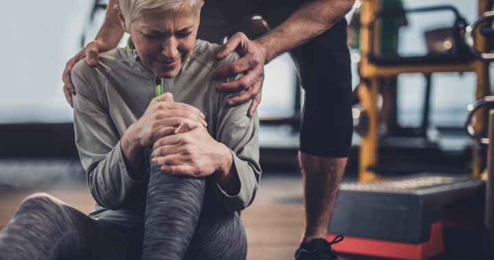 woman holding injured knee in pain