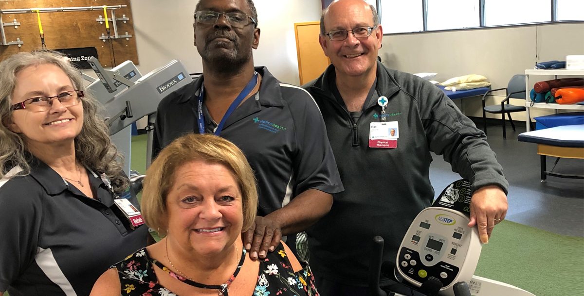 Deb Rogers, a Mercy Health Physical Therapy patient, sits in front of the orthopedic team members who helped her walk again