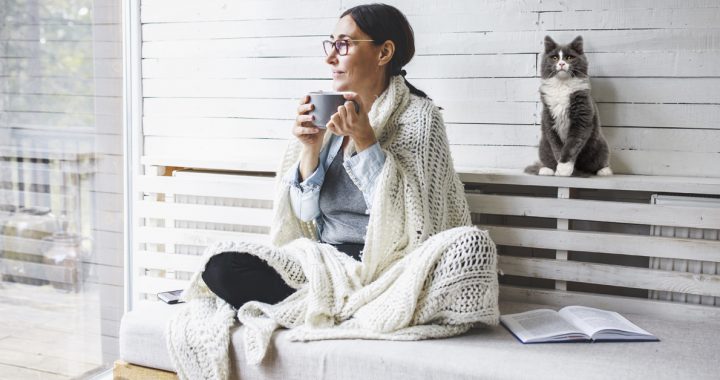 Woman relaxing on her porch with a cup of coffee and her cat.