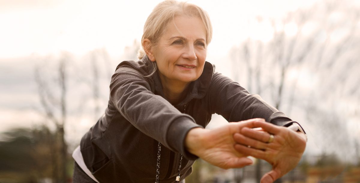 Woman practicing stretching exercises outside.