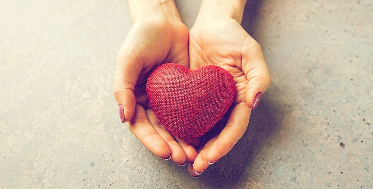 An individual holding a toy heart in their hands.