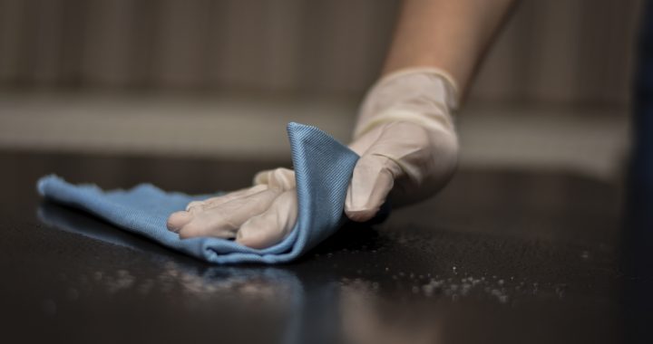 Person cleaning and disinfecting a surface in their home