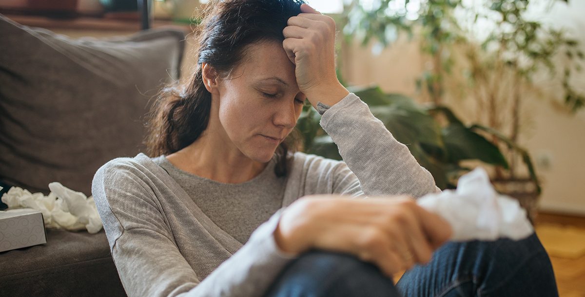 A woman sitting on the ground experiencing a headache