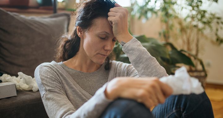 A woman sitting on the ground experiencing a headache