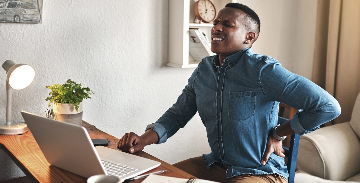 A man experiencing back pain while working from home during COVID-19.