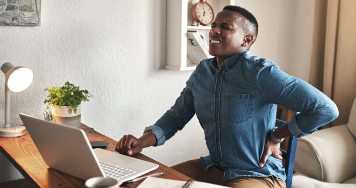 A man experiencing back pain while working from home during COVID-19.