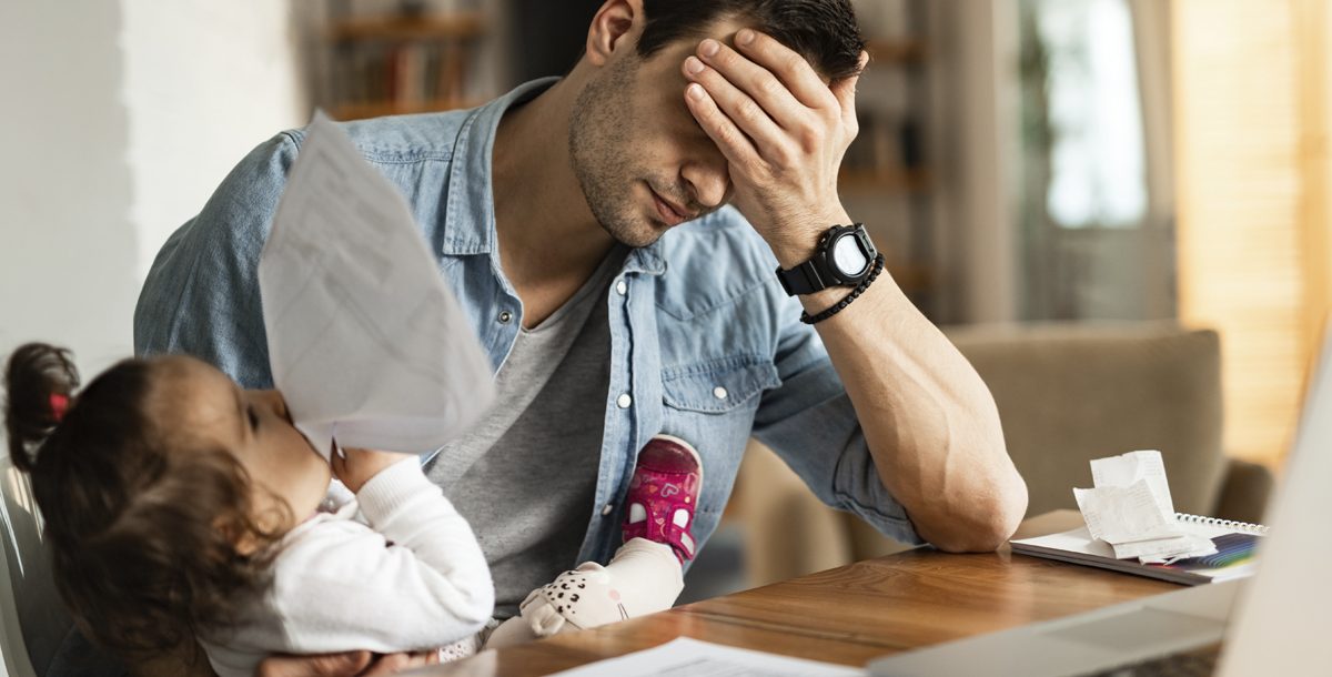 A father feeling stressed while taking care of his child.