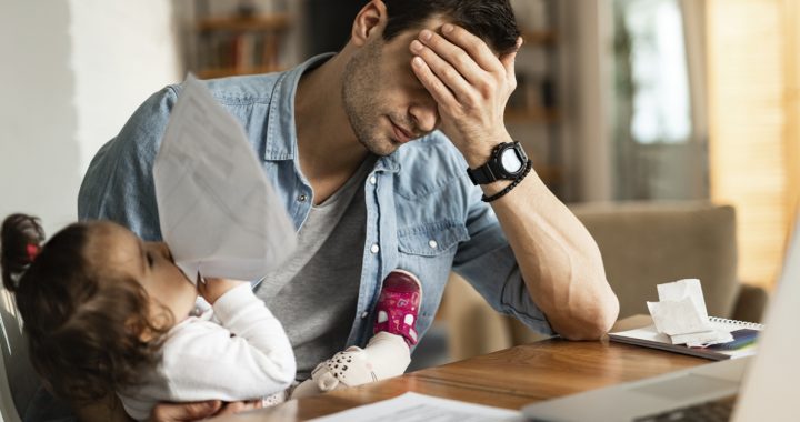 A father feeling stressed while taking care of his child.