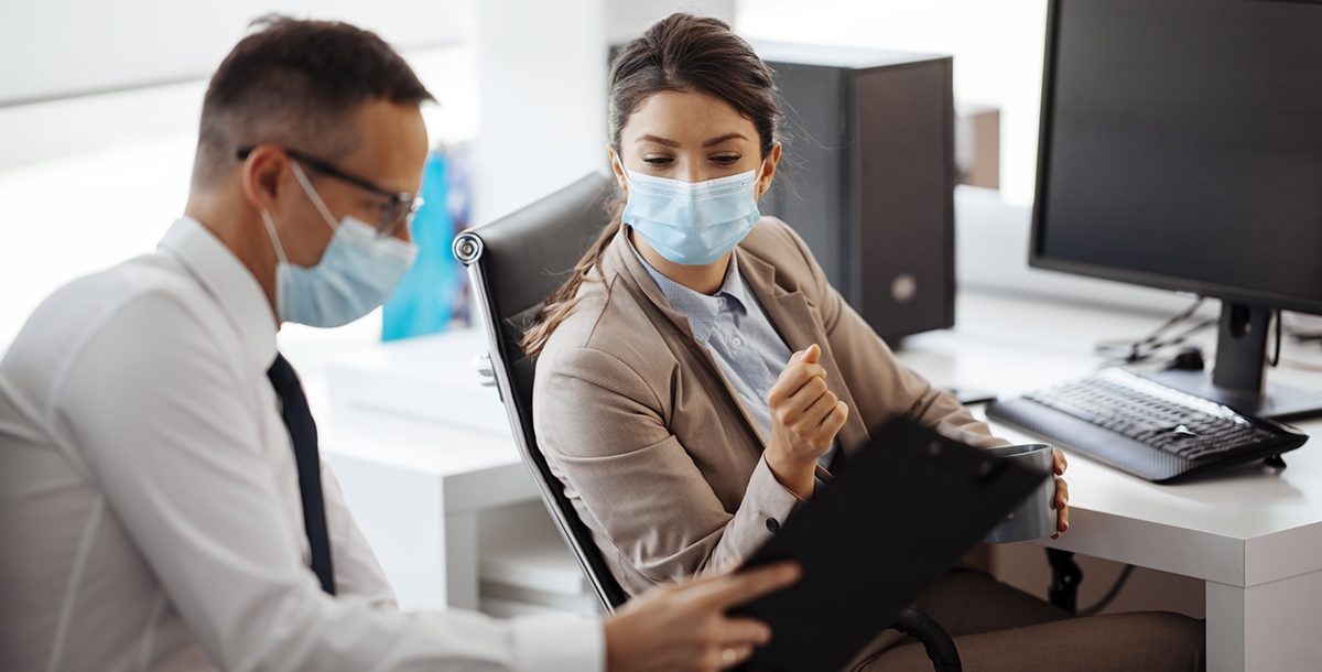 Two coworkers reviewing data together while wearing face masks.