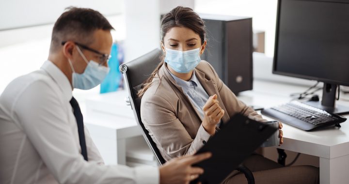 Two coworkers reviewing data together while wearing face masks.