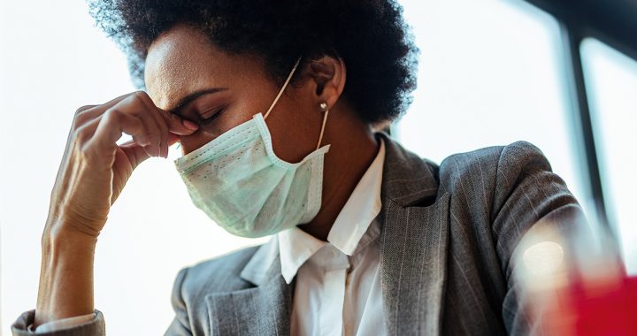 A woman experiencing a headache while wearing a face mask.