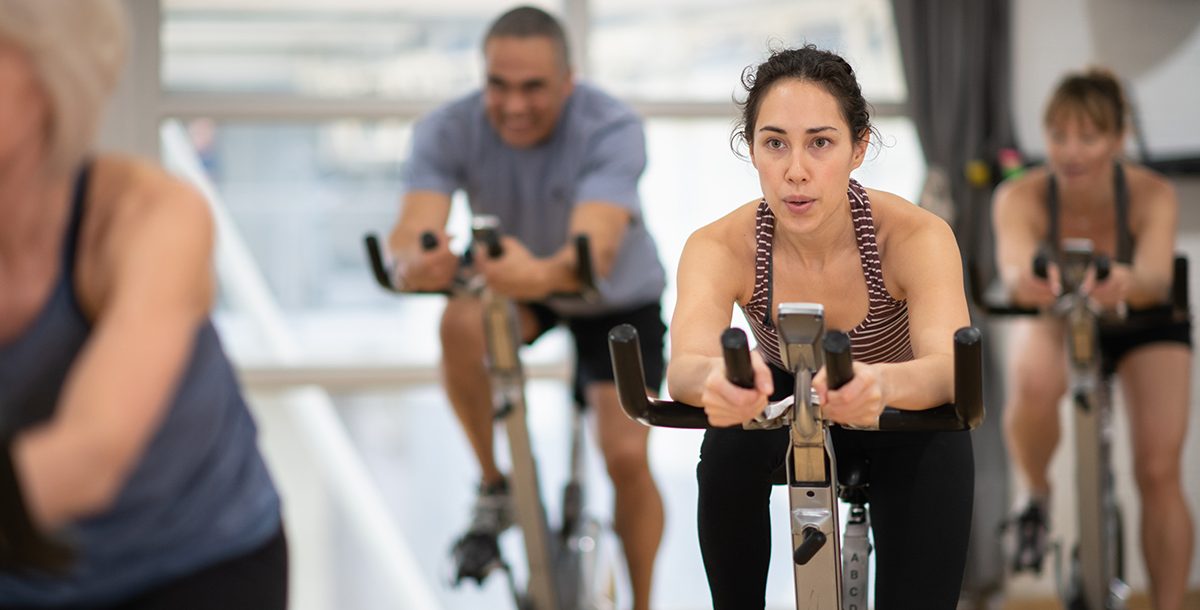 A woman participating in a cycle class at the gym during COVID-19.