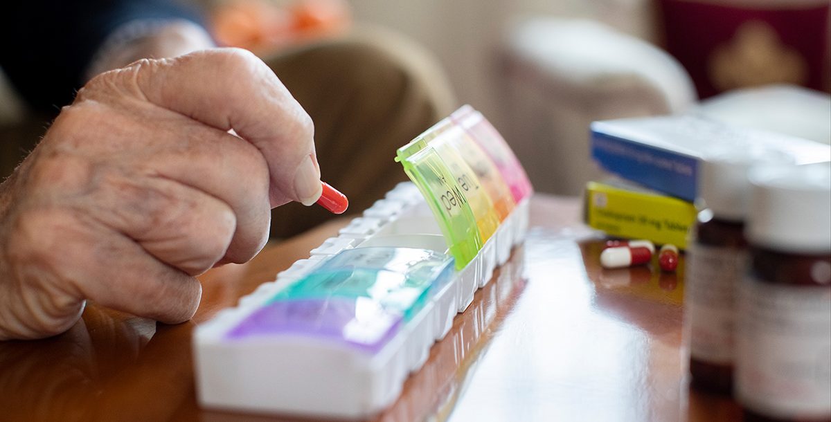 Someone using a pill organizer to manage their medications during COVID-19.