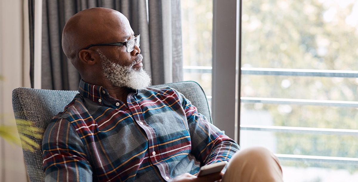 A man reflecting while looking out of his window.