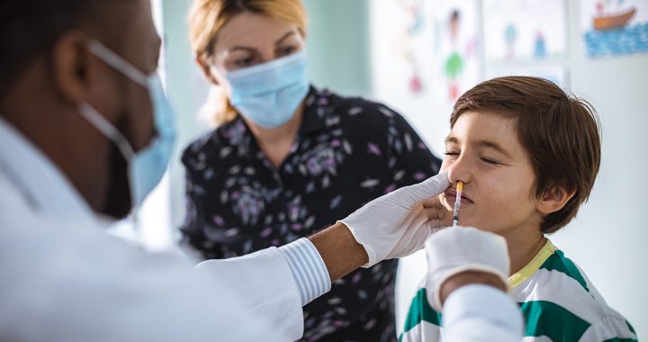 A kid getting the nasal spray flu vaccine from his primary care provider.