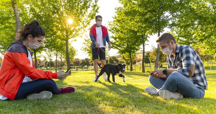 A group of people wearing face masks outdoors at a park.