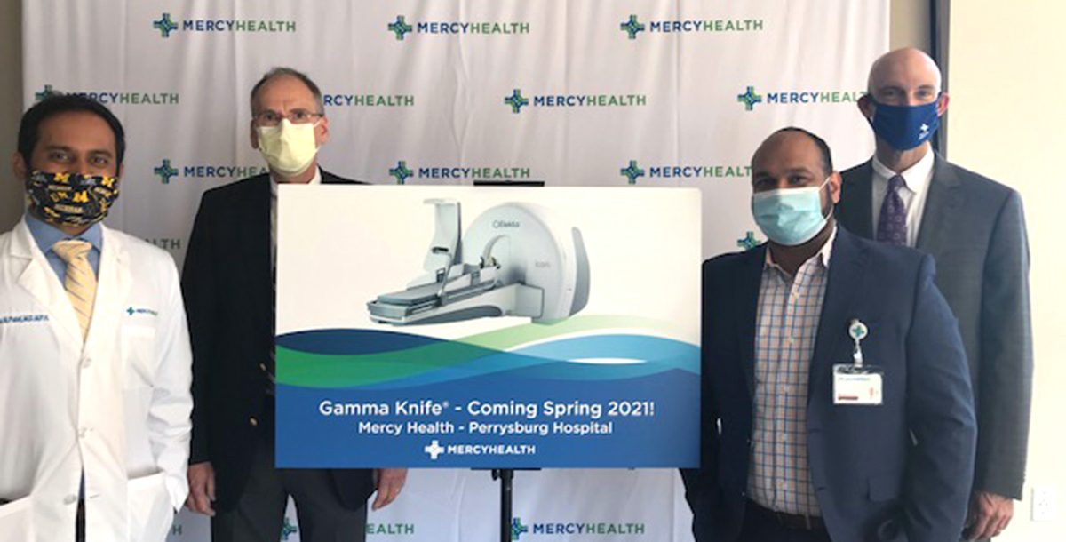 Mercy Health Perrysburg Hospital leadership team members stand surrounding a poster depicting a gamma knife machine