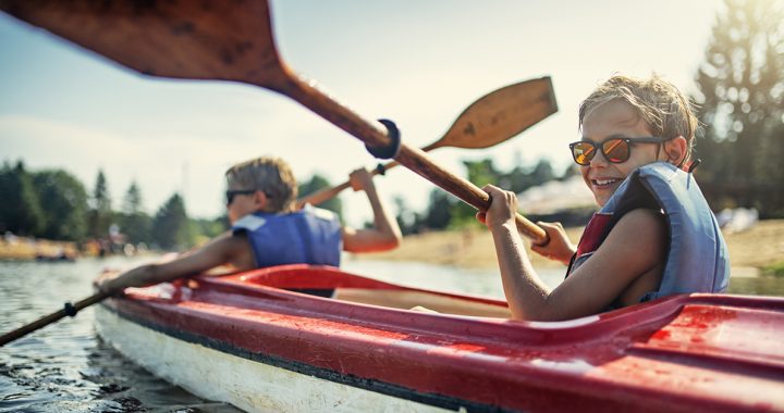 A child kayaking with their parent.