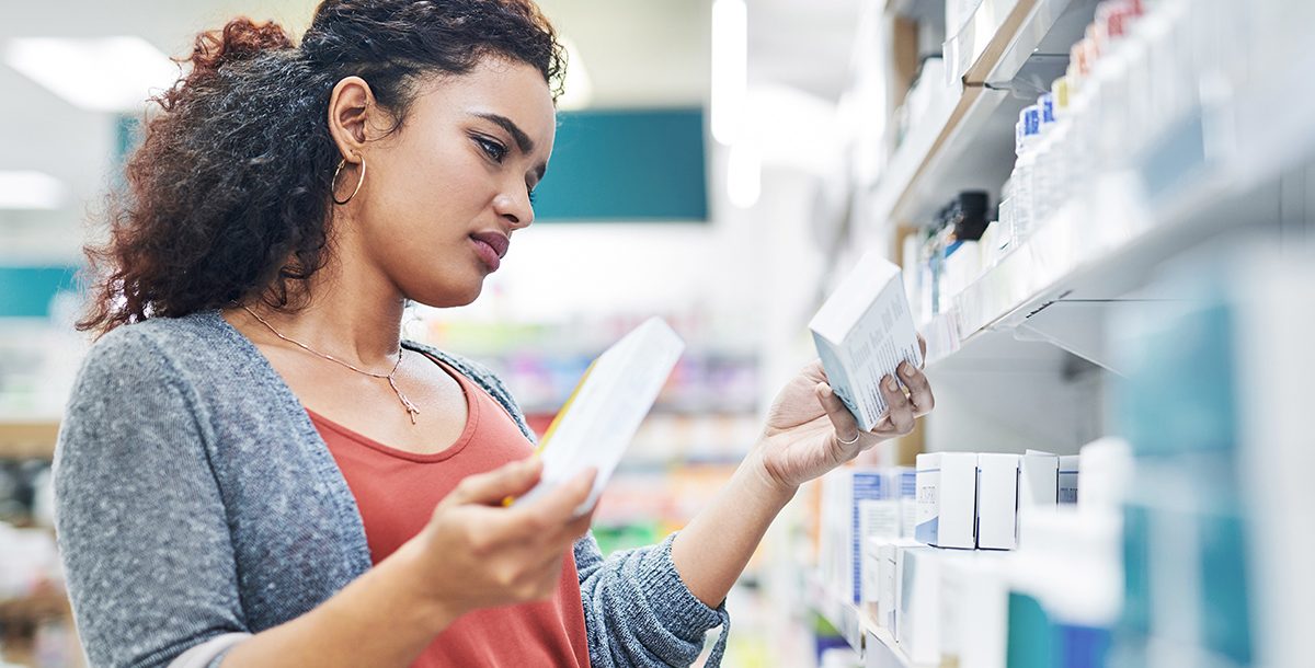 A woman looking at different medications at the pharmacy.