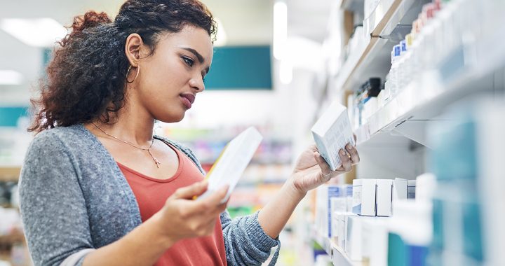 A woman looking at different medications at the pharmacy.