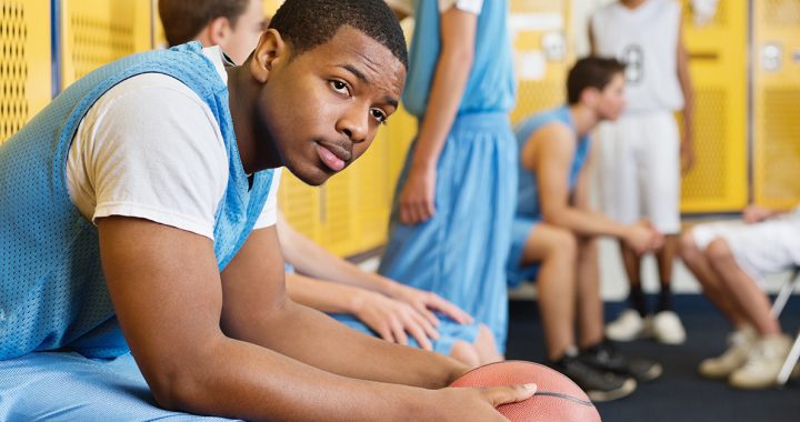 A high school athlete sitting in a locker room.