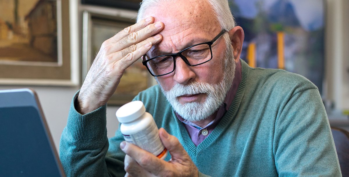 A man looking at a medication bottle.